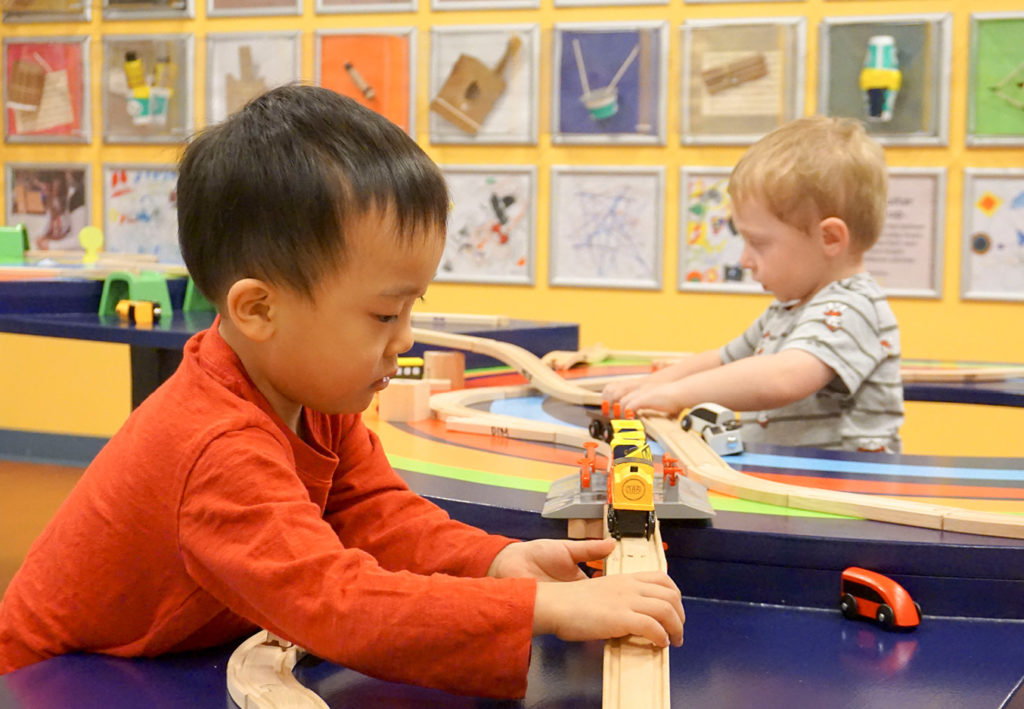 Children build wooden train tracks for toy trains in DCM Express