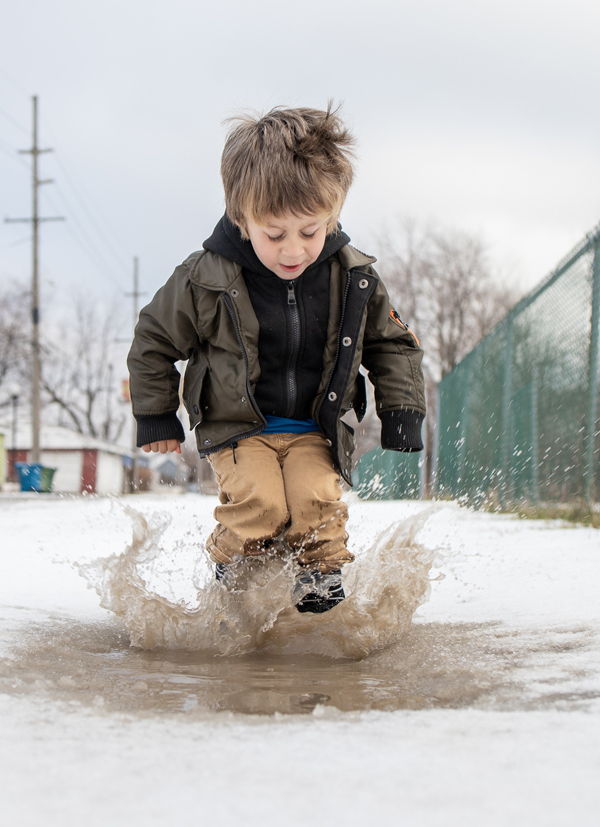 Young child jumping in puddle.